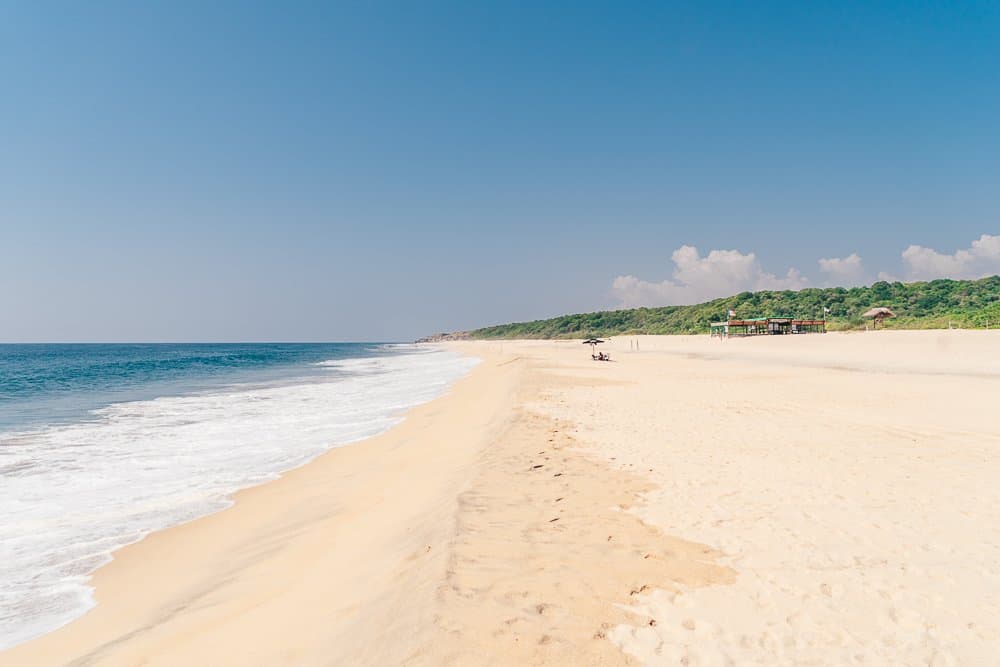 long sandy beach, blue water, blue sky