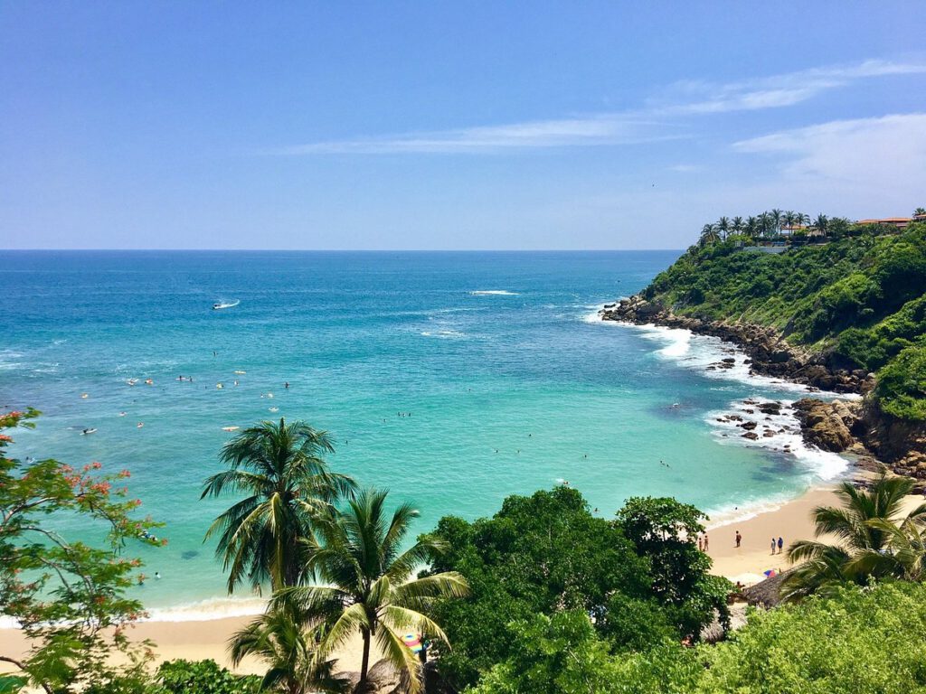 view form above to a bay with turquoise ocean, palm trees, and sand