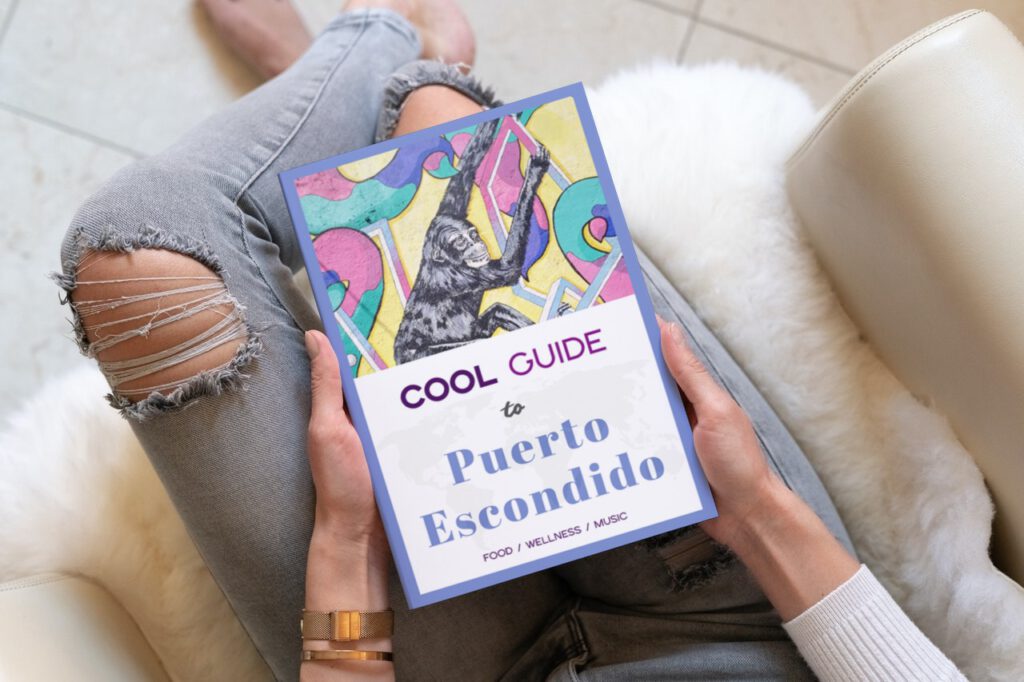 woman holding Cool Guide tp Puerto Escondido in her hands, wearing ripped jeans, and sitting in a light-colored chair