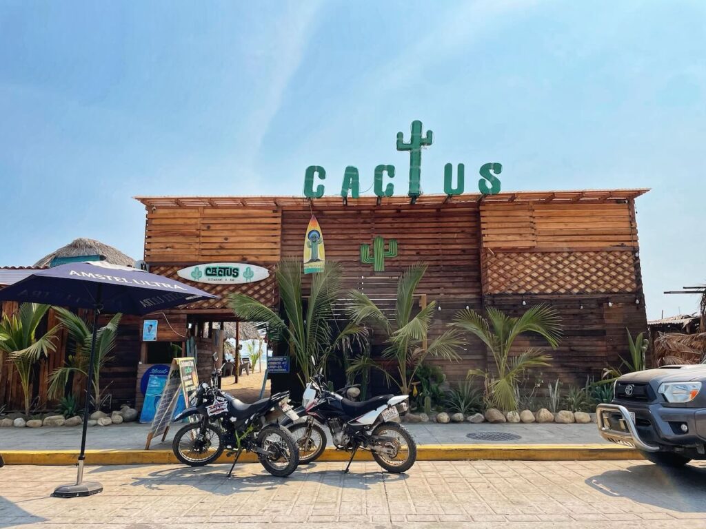 two motorbikes in front of a wooden restaurant / club with the letters Cactus on top