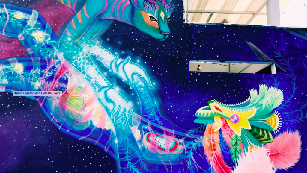 graffiti in Playa del carmen with blue and pink tones with a magical being of the stars coming down towards a green dragon, holding each other