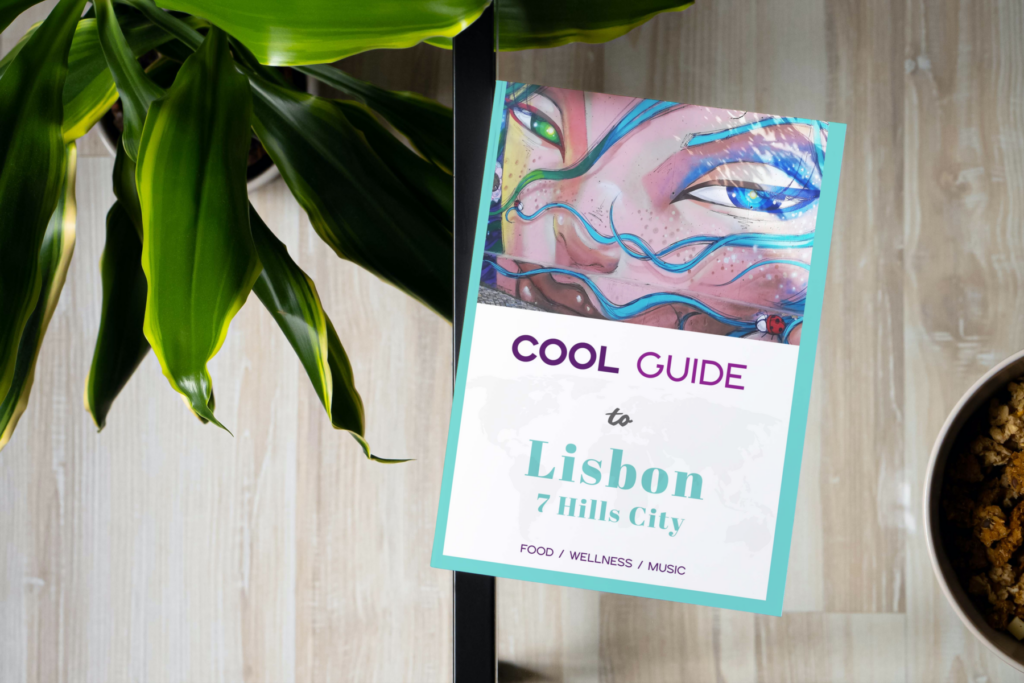 Travel guide to Lisbon with graffiti artwork on glass table next to green plant