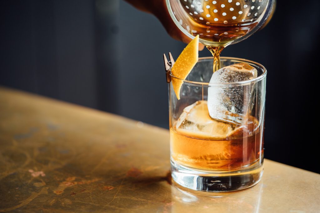 whiskey being poured into the glass with ice cubes