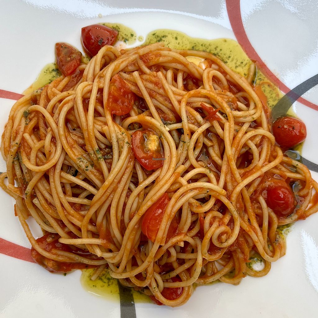 spaghetti on a plate with small tomatoes ad pesto tomato sauce